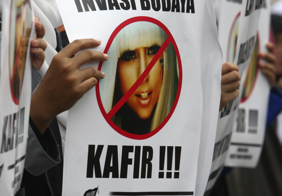 A Muslim woman holds a poster bearing a defaced picture of U.S. pop singer Lady Gaga during a protest against her concert that is scheduled to be held on June 3, in Jakarta, Indonesia, Thursday, May 24, 2012. Lady Gaga might have to cancel her sold-out show in Indonesia because police worry her sexy clothes and dance moves undermine Islamic values and will corrupt the country's youth. The writing on the poster reads "Infidel." (AP Photo/Tatan Syuflana)