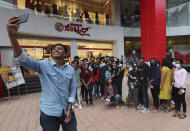 A group of young people, many wearing face masks as a precaution against COVID-19, pose for a selfie outside a shopping mall in Bengaluru, capital of the southern Indian state of Karnataka, Thursday, Dec. 2, 2021. India on Thursday confirmed its first cases of the omicron coronavirus variant in two men in Karnataka who came from abroad. (AP Photo/Aijaz Rahi)