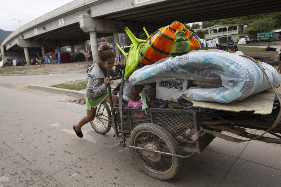 Floria Sarai Calix pushes her belongings in hopes of finding a safer area to camp out with her son after losing their home in the Chamelecon neighborhood to hurricanes Eta and Iota, on the outskirts of San Pedro Sula, Honduras, Monday, Jan. 11, 2021. The devastation wrought by November's hurricanes and the economic damage of the COVID-19 pandemic has added to the forces that drive Hondurans to migrate: poverty and gang violence. (AP Photo/Moises Castillo)