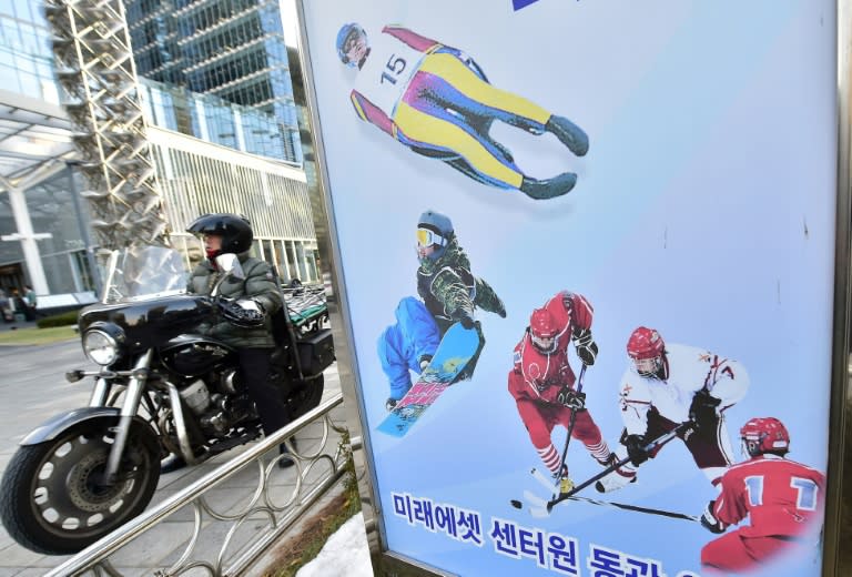 A man riding a motorbike passes a signboard for the 2018 Pyeongchang Winter Games in Seoul on December 8, 2014