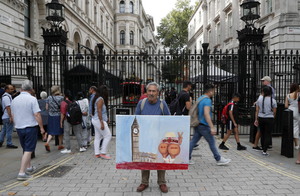 Artist Kaya Mar protests with a picture at the gate of Downing Street in London, Wednesday, Aug. 28, 2019. Prime Minister Johnson has written to fellow lawmakers explaining his decision to ask Queen Elizabeth II to suspend Parliament as part of the government plans before the Brexit split from Europe. (AP Photo/Frank Augstein)