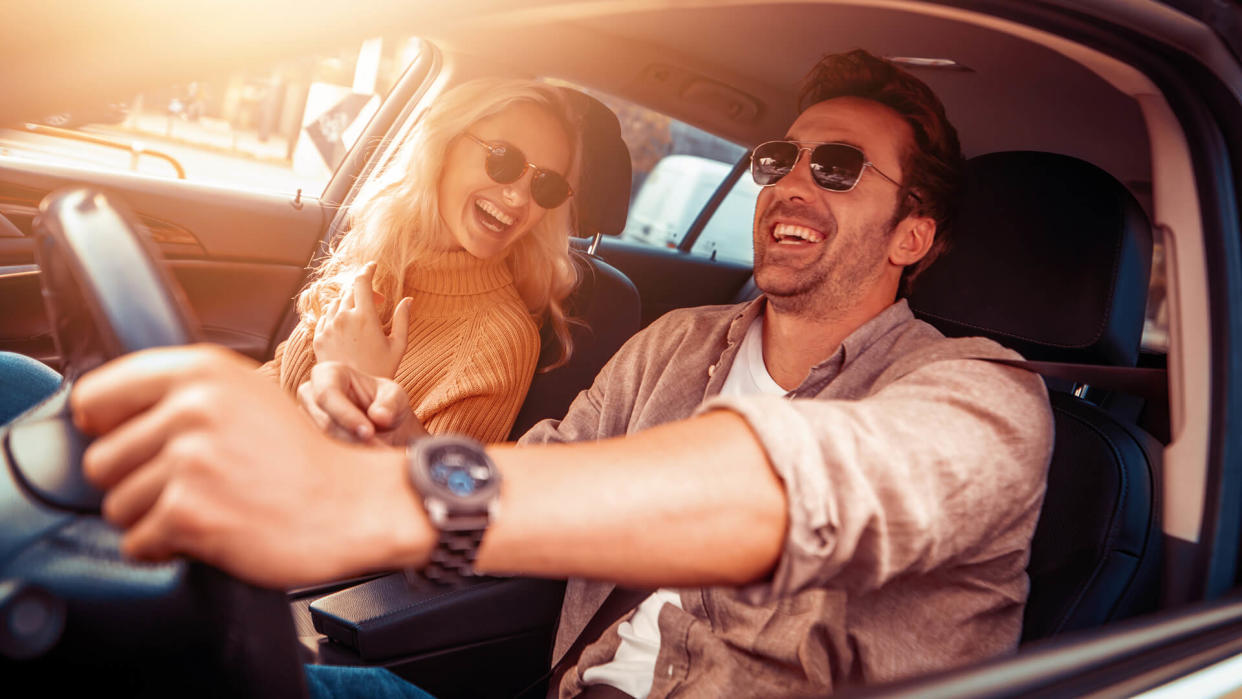 Happy young couple enjoying on a long drive in a car.