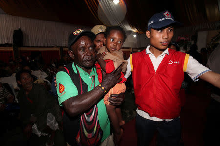 A member of the Indonesian Red Cross (R) assists evacuees from villages authorities said had been occupied by armed separatists, near the Grasberg copper mine operated by Freeport McMoRan Inc, in Timika, Mimika, Papua province, Indonesia November 17, 2017. REUTERS/Muhammad Yamin