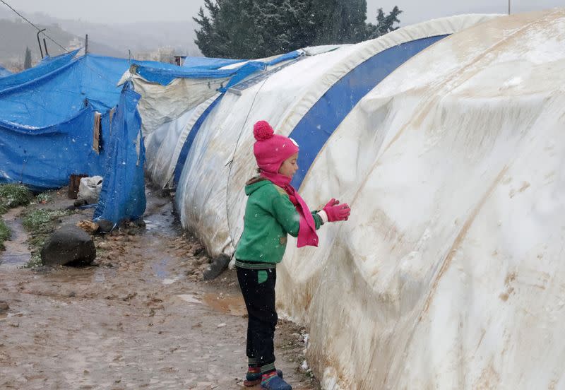 FILE PHOTO: Internally displaced Syrian child plays with snow, at a camp in Northern Aleppo countryside