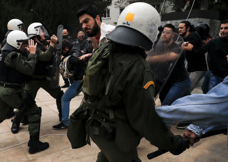 A riot police officer clashes with Greek Communist Party supporters who tried to bring down a statue of former U.S. President Harry Truman, seen in the background, during a demonstration against air strikes on Syria by the United States, Britain and France, in Athens, Greece April 16, 2018. REUTERS/Alkis Konstantinidis