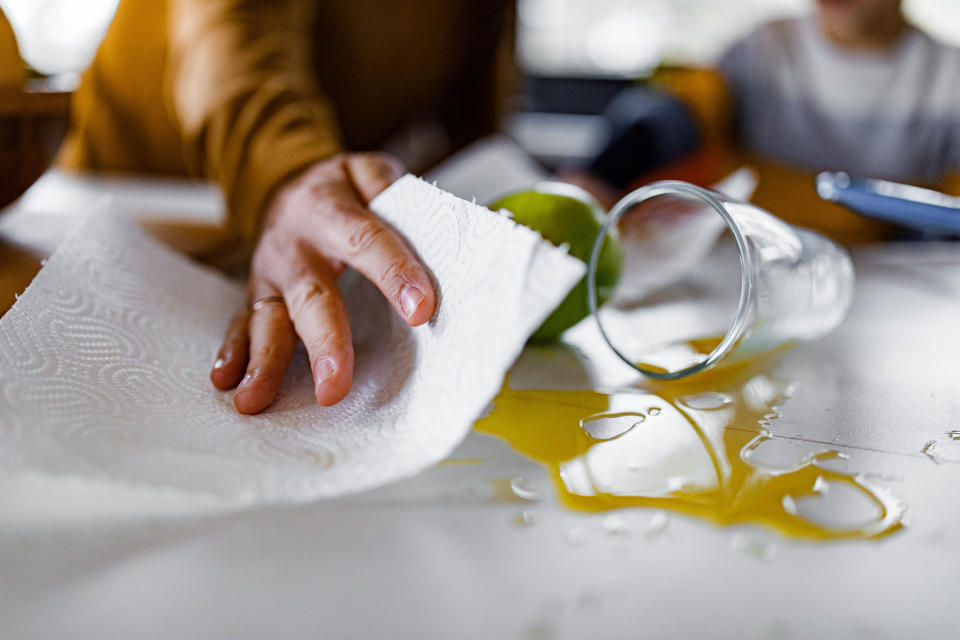 Closeup of a hand cleaning up spilled juice with a paper towel