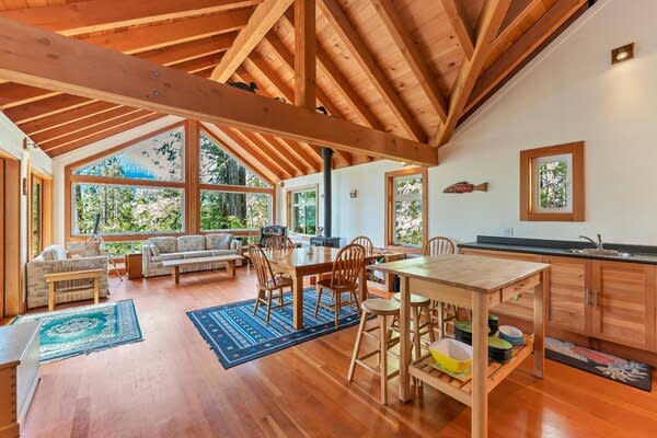 The lodge-like residence radiates warm, rustic vibes, featuring vaulted wood ceilings, exposed beams, and refinished hardwood floors.