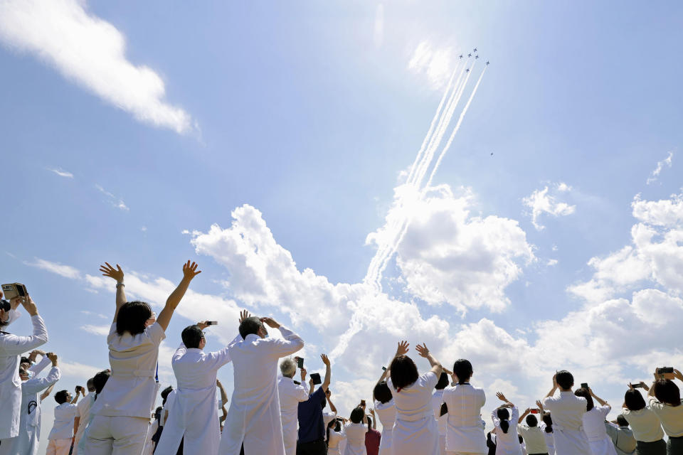 Blue Impulse of the Japan Air Self-Defense Force fly over medical workers of Self-Defense Forces Central Hospital in Tokyo, Friday, May 29, 2020, in Tokyo. A Japanese Air Self-Defense Force’s aerobatics team performed a demonstration flight to express support and gratitude for medical workers. The six Blue Impulse aircraft flew for about 20 minutes over Tokyo to thank for doctors, nurses and other medical staff. (Kyodo News via AP)