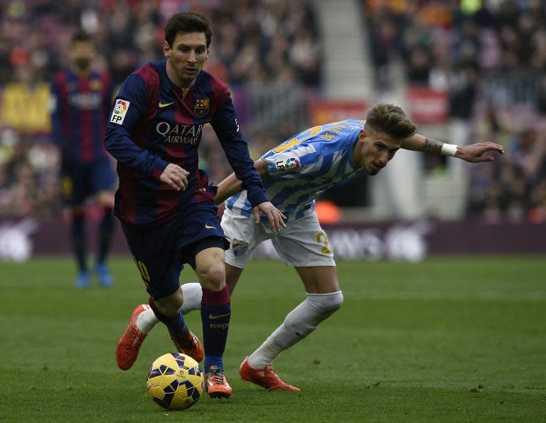 Barcelona's Lionel Messi (L) fights for the ball with Malaga's Samuel Castillejo during their Spanish La Liga match, at the Camp Nou stadium in Barcelona, on February 21, 2015