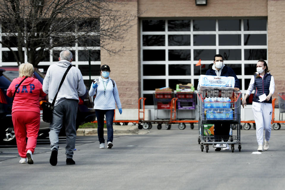 Shoppers enter and exit Costco for grocery shopping as they wear face masks and gloves during the coronavirus outbreak in Northbrook, Ill., Saturday, April 11, 2020. (AP Photo/Nam Y. Huh)