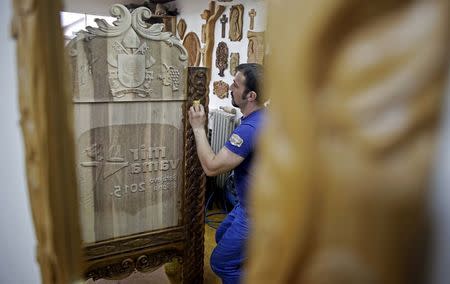 A reflection in a mirror shows Bosnian wood carver-sculptor Edin Hajderovac working on a chair for Pope Francis, at his workshop in Zavidovici, Bosnia and Herzegovina, in this May 25,2015 file photo. Even before arriving in Sarajevo, Pope Francis has achieved a remarkable feat. Preparing for the visit, Bosnians of all faiths are showing a rare unity in a country plagued by political and ethnic tensions nearly 20 years after the end of its 1992-95 war that claimed over 100,000 lives. While the pontiff's June 6 visit is the most eagerly awaited by Catholic Croats, the smallest group in the ethnically segmented state, Orthodox Serbs and Muslim Bosniaks have also taken an active part in preparing a warm welcome for Francis. REUTERS/Dado Ruvic/Files