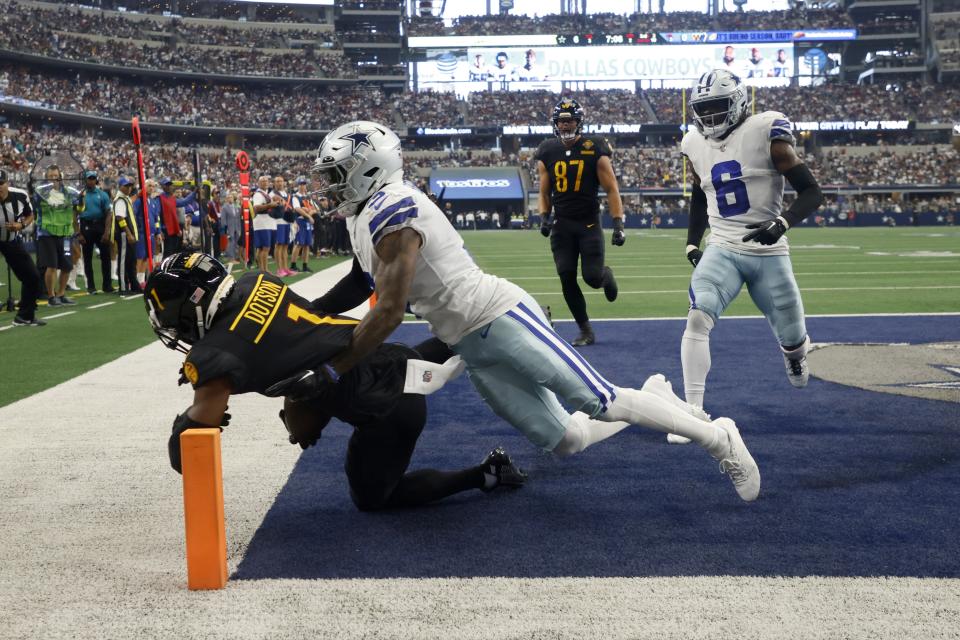 Washington Commanders wide receiver Jahan Dotson (1) catches a touchdown pass as Dallas Cowboys cornerback Anthony Brown (3) and Donovan Wilson (6) defend in the first half of a NFL football game in Arlington, Texas, Sunday, Oct. 2, 2022. The Commanders' John Bates looks on from the rear. (AP Photo/Michael Ainsworth)