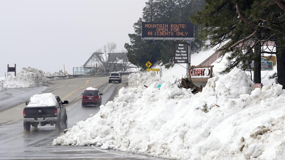 Mounds of snow cover the sides of the main road leading out of the mountains after a series of storms Wednesday, March 8, 2023, in Lake Arrowhead, Calif. Residents of Southern California mountain towns are still struggling to dig out and get necessities in the aftermath of a record-setting blizzard last month that dumped so much snow that roads became impassable and roofs collapsed. (AP Photo/Marcio Jose Sanchez)