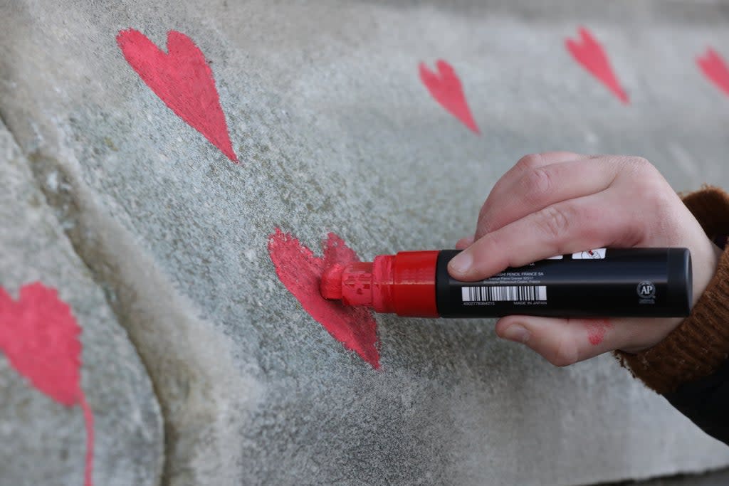 Bereaved families paint red hearts on the Covid memorial wall opposite the Houses of Parliament in London (Lucianna Guerra/PA) (PA Wire)