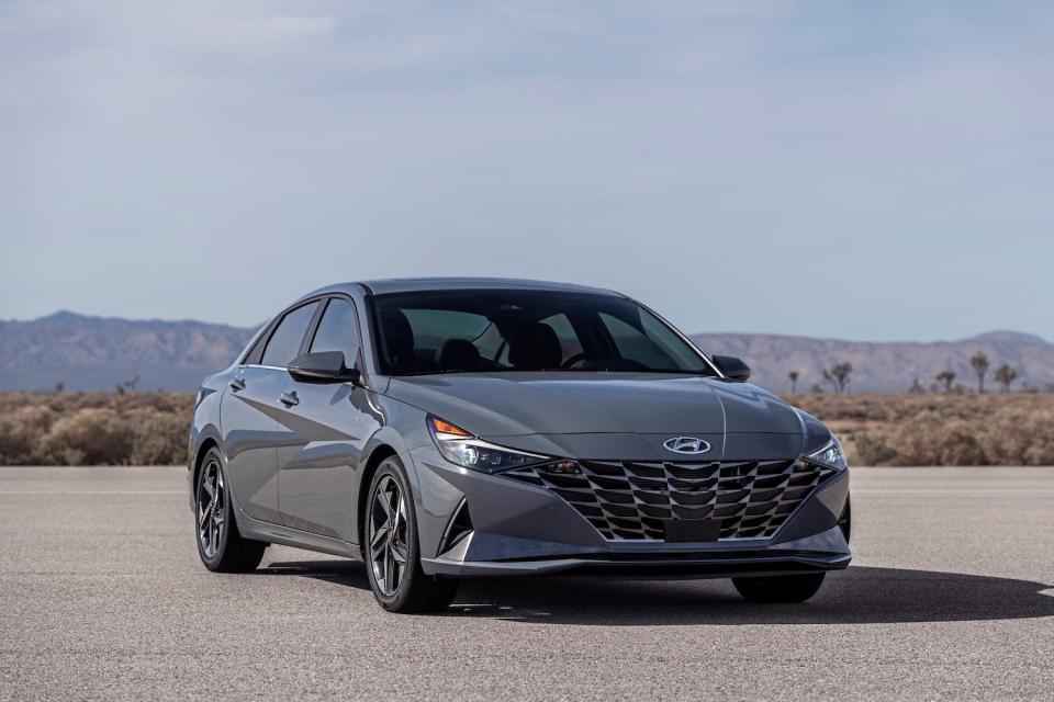 A 2023 Hyundai Elantra Hybrid is parked in an empty lot against a mountainous backdrop.