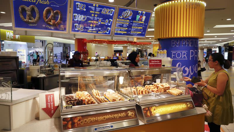 In this Tuesday, Oct. 18, 2016 photo, a customer purchases a pretzel at Auntie Anne’s at a shopping mall in Kuala Lumpur, Malaysia.