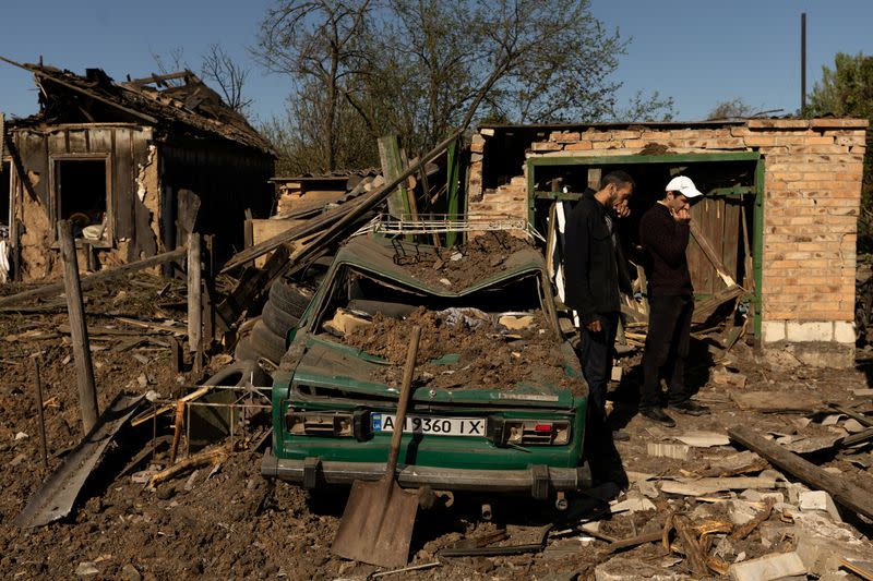 Men react as they stand stand in front of their house after a missile strike hit a residential area in Bakhmut in the Donetsk region