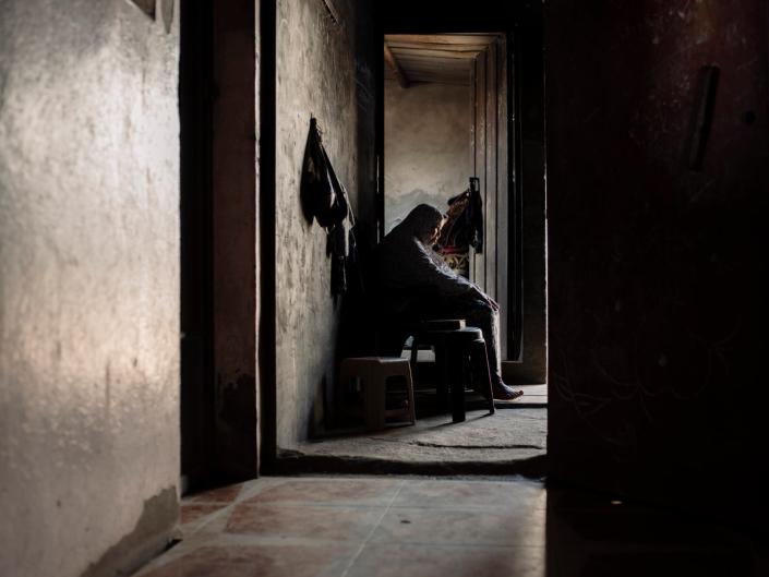 An elderly lady sits near the entrance to her family home, waiting for any breeze to cut through the relentless coastal humidity (Paddy Dowling)