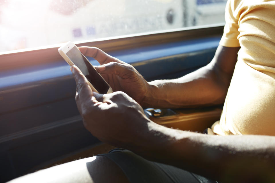 Close-up of hands holding smartphone inside car at sunset