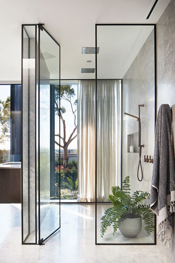 <p>Just because you can't invest in an outdoor shower doesn't mean you can't make your bathroom feel like it's outside. Play up garden views with modern glass doors and windows (and let the light pour in), and introduce some greenery in the shower. Plants help <a href="https://www.housebeautiful.com/design-inspiration/home-makeovers/a25647661/room-makeover-plants/" rel="nofollow noopener" target="_blank" data-ylk="slk:rid the air of chemicals;elm:context_link;itc:0;sec:content-canvas" class="link ">rid the air of chemicals</a> left behind by cleaning and beauty products. Plus—they instantly add life to any bathroom. Then add some curtains for privacy, as design firm Hecker Guthrie did here. </p>