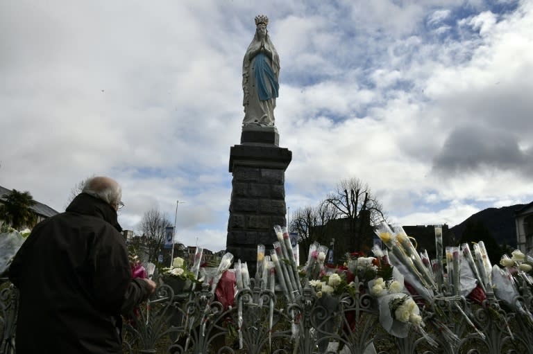 A pilgrim puts flowers in front of a statue of the Virgin Mary in the sanctuary of Lourdes, southern France on February 11, 2016 for the 158th anniversary of the virgin Mary's apparition to Bernadette Soubirous