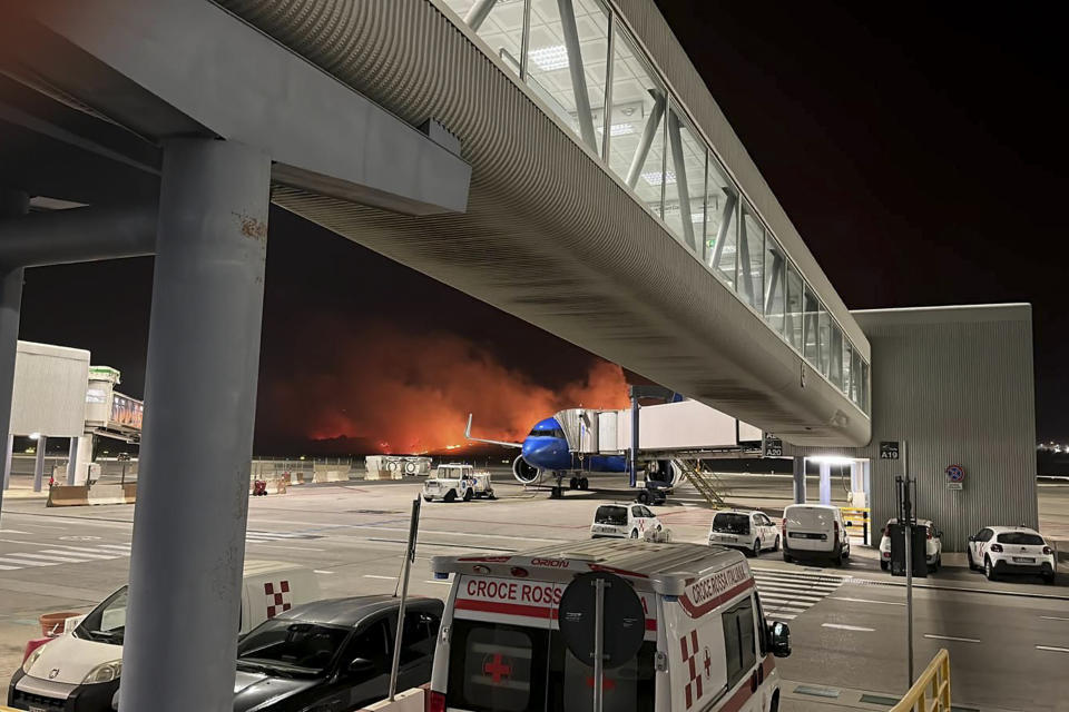 This photo provided by Palermo Airport Press Office shows plumes of fire and smoke covering the hills surrounding Palermo's airport, Sicily, Italy, late Monday night, July 24, 2023, causing its shutdown and leaving planes trapped on the tarmac. The airport reopened at 11am (9gmt) Tuesday 25 only for departing planes, after twentyfour flights were cancelled overnight and four were sent to the nearby airport in Trapani. (Palermo Airport Press Office via AP)