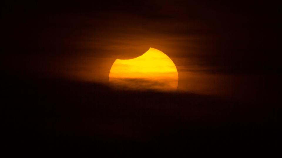 A total solar eclipse observed in Montevideo, Uruguay. The image was taken outdoors, with no people in the image. The sun is also setting on the horizon over the Rio de La Plata.