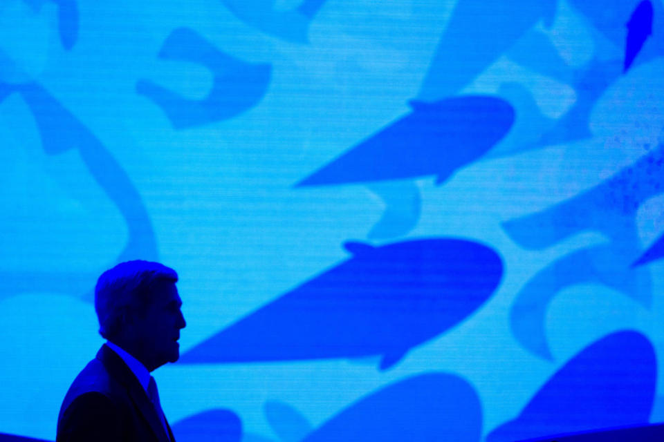 Secretary of State John Kerry stands onstage against a video backdrop of ocean life