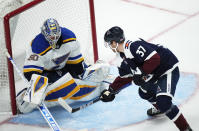 St. Louis Blues goaltender Jordan Binnington, left, stops a shot off the stick of Colorado Avalanche left wing J.T. Compher in the first period of an NHL hockey game Saturday, Oct. 16, 2021, in Denver. (AP Photo/David Zalubowski)