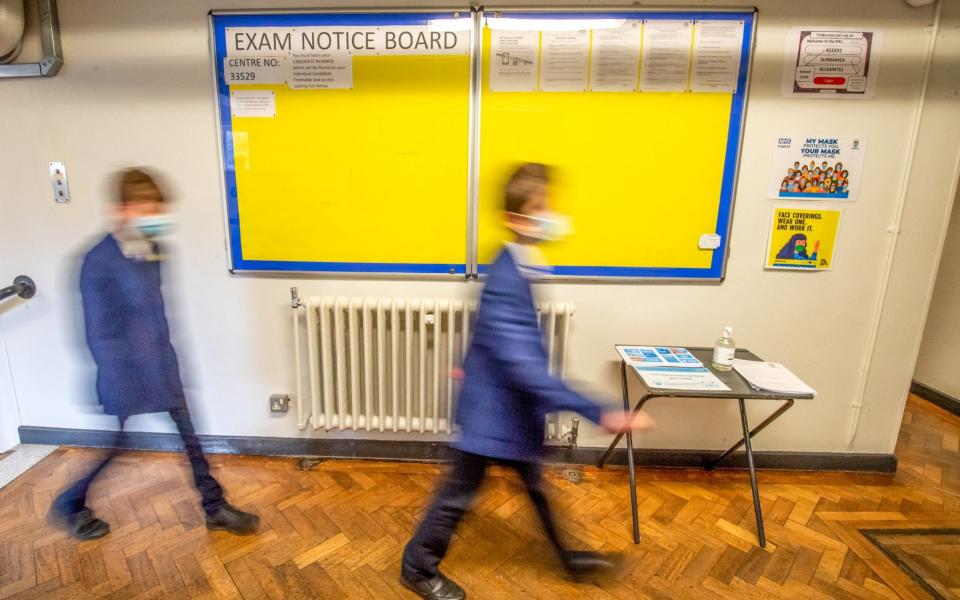 Pupils wearing face masks walk past an empty exams notice board  - Anthony Devlin/Bloomberg