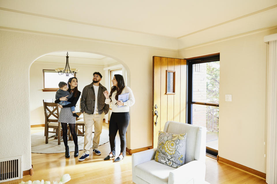 real estate agent walking a young couple with a baby through a house