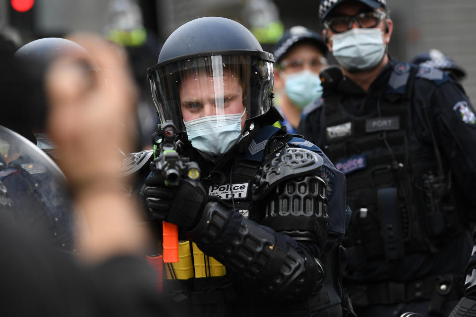 Police are seen in riot gear during an anti-lockdown protest on Saturday as an officer aims his weapon at demonstrators. Source: AAP