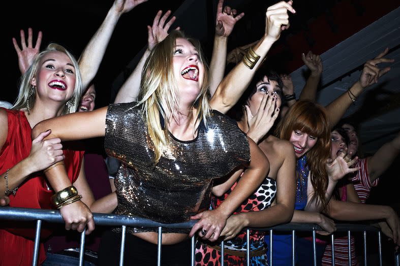 a group of fans screaming and dancing at a concert