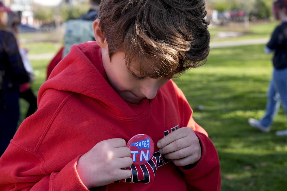 Myles Steinberg, 11, puts on a pin at the Linking Arms for Change human chain Wednesday, March 27, 2024, in Nashville, Tenn. The event was to commemorate the one-year anniversary of the Covenant School mass shooting. (AP Photo/George Walker IV)