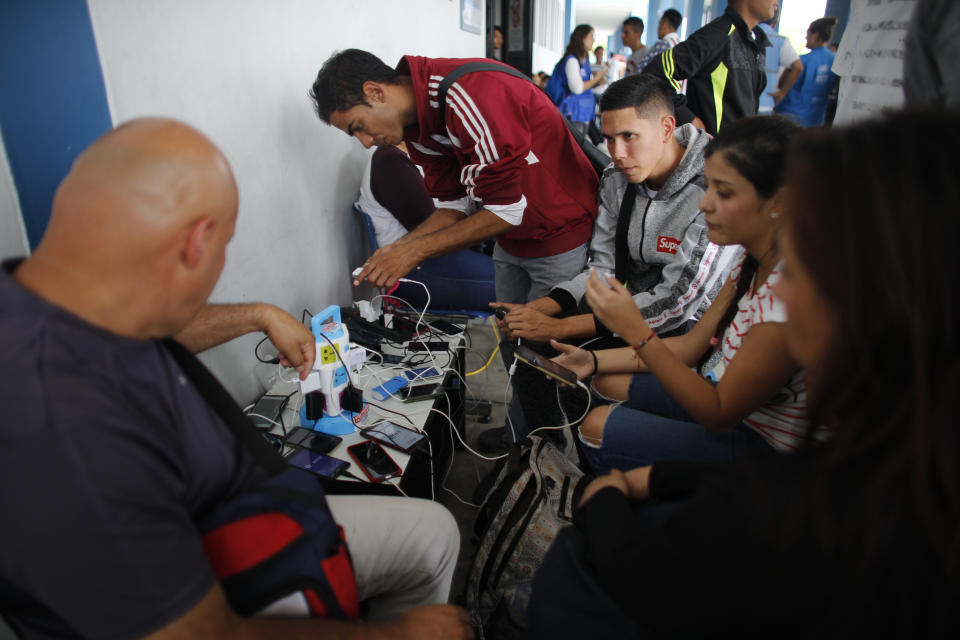 En esta imagen, tomada el 7 de septiembre de 2018, venezolanos cargan sus celulares gratis en una oficina de inmigración en Aguas Verdes, Perú. Los celulares son un lujo que muchos migrantes pobres que se echan a caminar no tienen. (AP Foto/Ariana Cubillos)