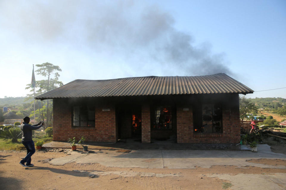 A man uses a cellphone to take pictures of a burning school office in Mashau Dolly village, in South Africa’s Limpopo province, May 5, 2016. (Siphiwe Sibeko/REUTERS)