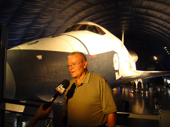 Fred Haise, Jr., veteran NASA astronaut, answers a reporter's questions with shuttle Enterprise in the background at the new Intrepid Museum exhibit. Photo taken July 18, 2012.