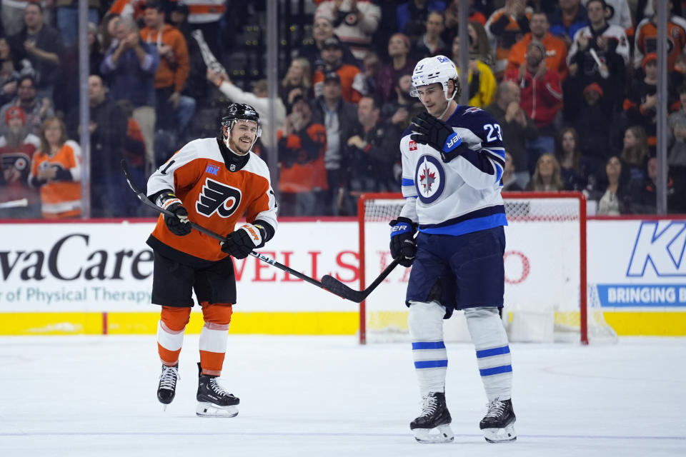 Philadelphia Flyers' Travis Konecny, left, reacts past Winnipeg Jets' Sean Monahan after scoring a goal during the first period of an NHL hockey game, Thursday, Feb. 8, 2024, in Philadelphia. (AP Photo/Matt Slocum)