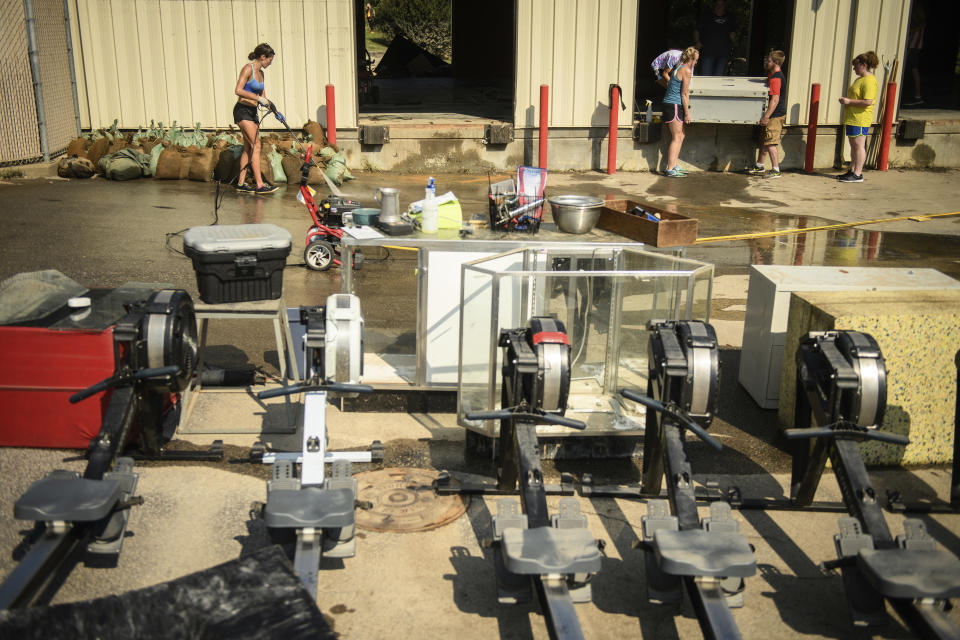 Izdihar Eaton sprays down an area before cleaning off equipment as others clear out the building at Evolution Athletics, Thursday, Sept. 20, 2018, on Bragg Boulevard in Spring Lake, N.C. The business was overcome by floodwaters from the Little River. (Andrew Craft/The Fayetteville Observer via AP)