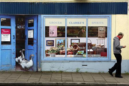 A man walks past an empty shop, which has been covered with artwork to make it look more appealing, in the village of Bushmills on the Causeway Coast August 19, 2013. REUTERS/Cathal McNaughton