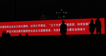 A paramilitary policeman standing guard is silhouetted on a large screen showing propaganda slogans on Tiananmen square next to the Great Hall of the People, where the closing ceremony of the Chinese Communist Party plenum is going to be held on Tuesday, in Beijing, November 11, 2013. REUTERS/Kim Kyung-Hoon