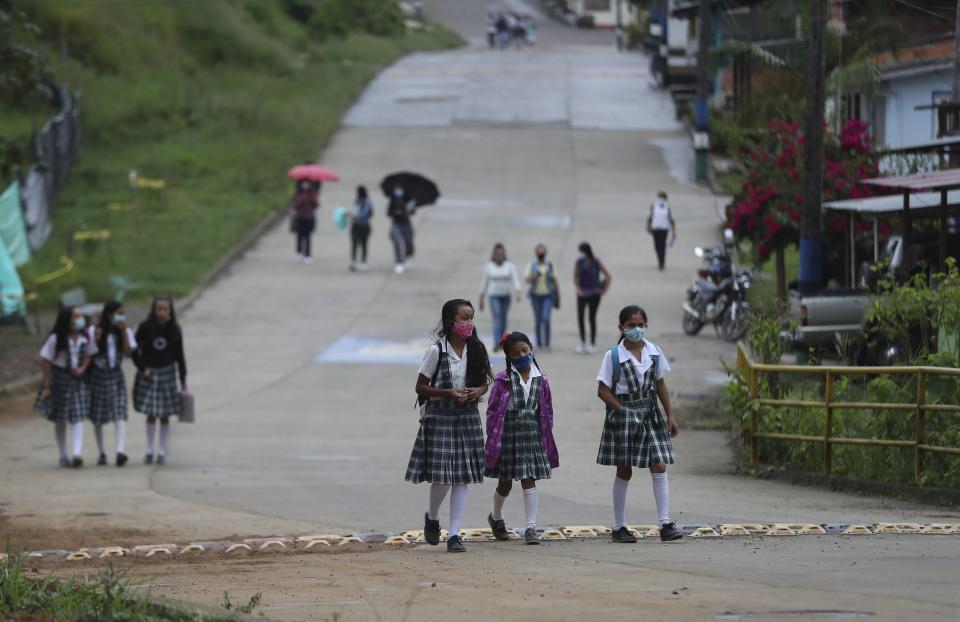 Wearing masks to curb the spread of the new coronavirus, students walk to the one open school in Campohermoso, Colombia, Thursday, March 18, 2021. Campohermoso is one of two municipalities in Colombia that has not had a single case of COVID-19 since the pandemic started one year ago, with the student body at the school rotating half the students into their classrooms while the other attends via the internet. (AP Photo/Fernando Vergara)