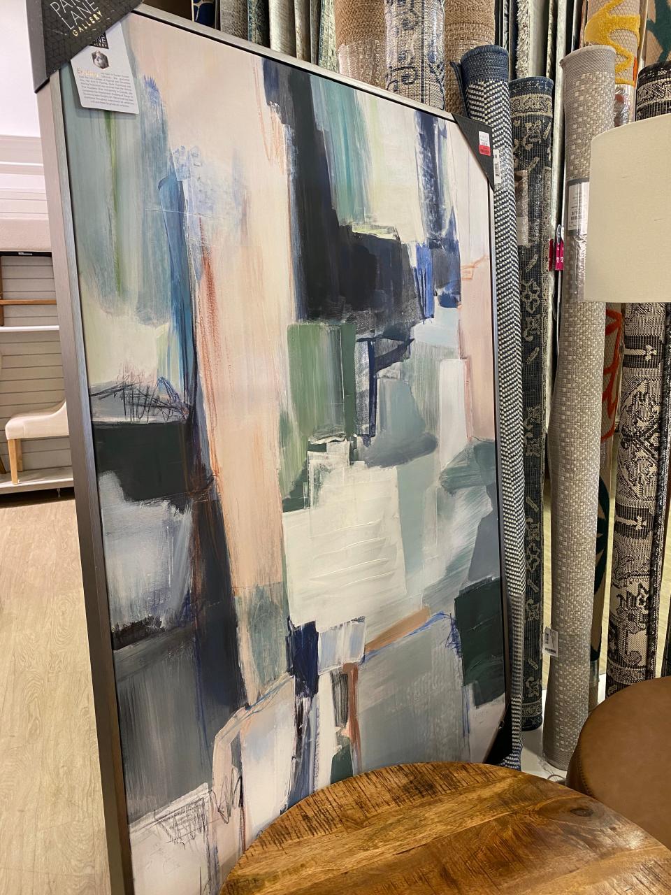 a large piece of artwork with paint brushstrokes in blue, gray, peach propped on the floor of a homegoods