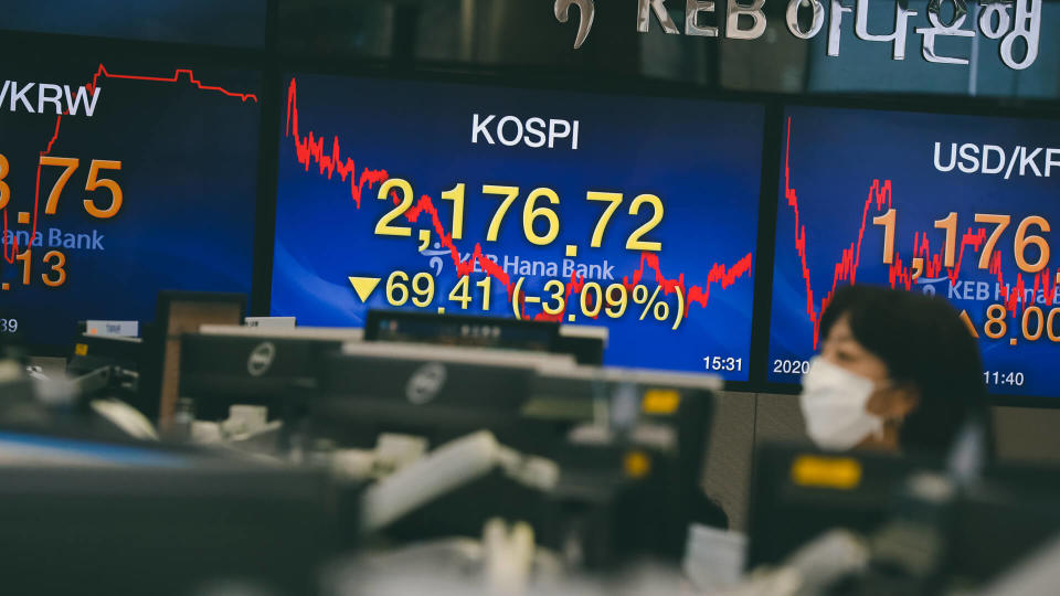 A person wearing a protective mask works in front of monitors, displaying the KOSPI, at the KEB Hana Bank in Seoul, South Korea, 28 January 2020.