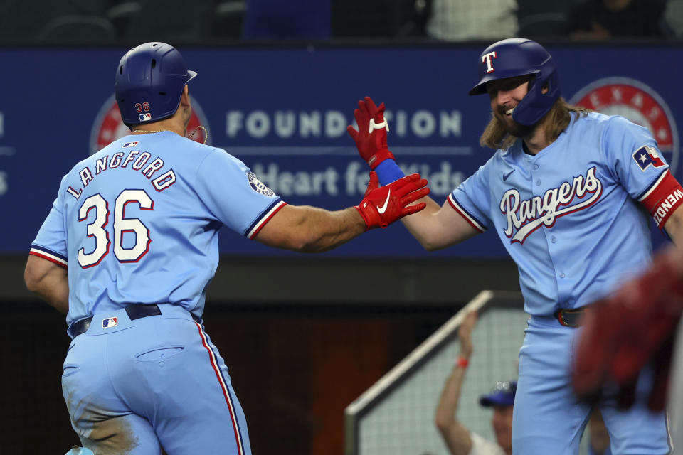 Texas Rangers's Wyatt Langford (36) celebrates with teammate Davis Wendzel, right, after hitting an inside-the-park home run against the Cincinnati Reds in the first inning of a baseball game Sunday, April 28, 2024, in Arlington, Texas. (AP Photo/Richard W. Rodriguez)