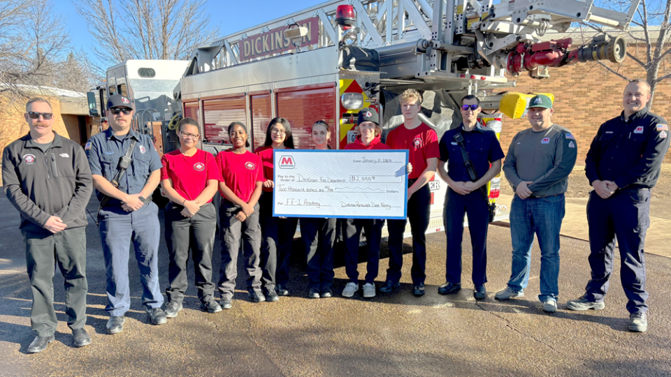 At the grant check presentation, (L-R) Dickinson Lieutenant Dustin Hofer, Dickinson Senior Firefighter Mason Gieger, (in red shirts) students enrolled in the Firefighter 1 Academy course, Dickinson Firefighter Matthew Davenport, Dickinson Renewable Diesel Facility Manager Nick Bear and Dickinson Renewable Diesel Facility Interim Fire Chief Nate Eberle.