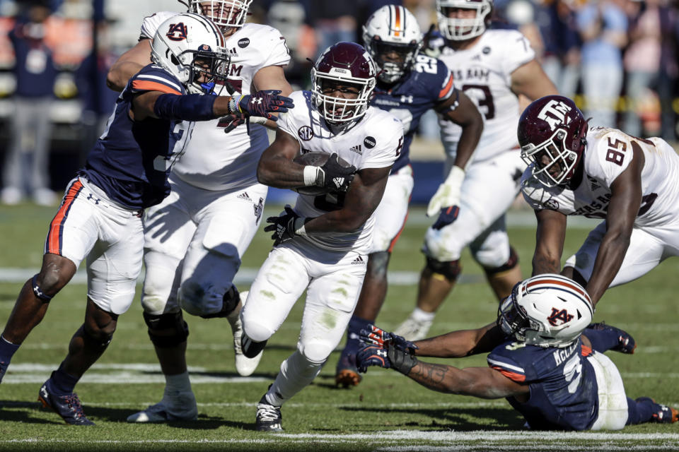 Texas A&M running back Devon Achane (6) carries the ball as Auburn defensive back Jaylin Simpson (36) and linebacker Zakoby McClain (9) try and stop him during the second half of an NCAA college football game on Saturday, Dec. 5, 2020, in Auburn, Ala. (AP Photo/Butch Dill)