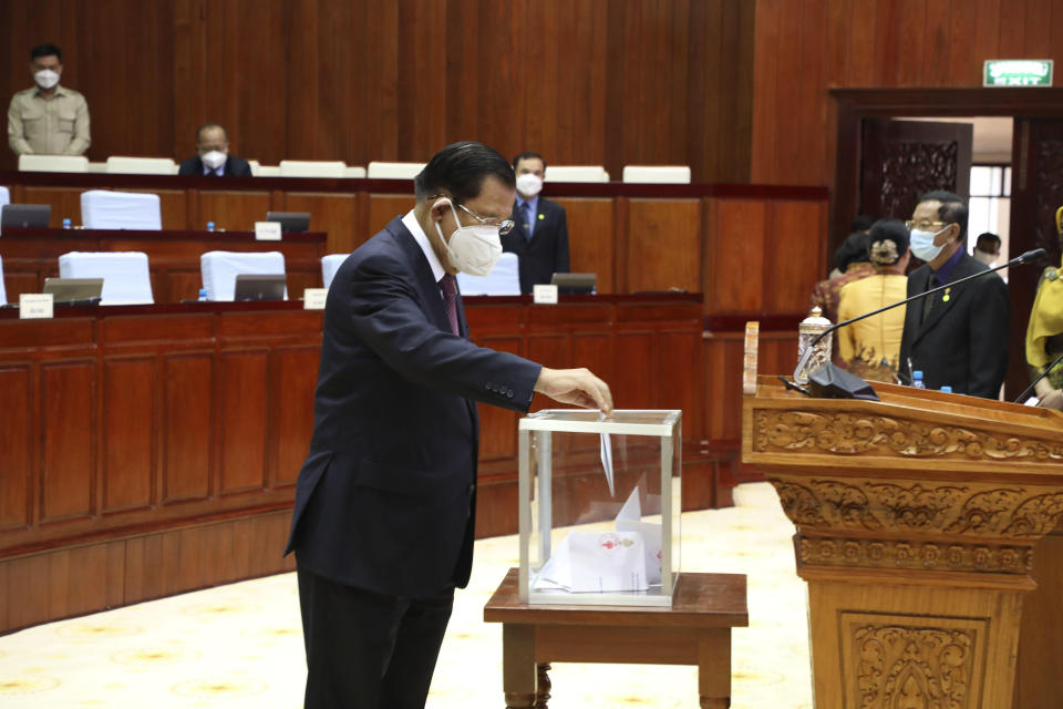 In this photo released by Cambodia's National Assembly, Cambodian Prime Minister Hun Sen drops a ballot into a box in the National Assembly hall in Phnom Penh, Cambodia, Monday, Oct. 25, 2021. Lawmakers in Cambodia on Monday approved amending the constitution to bar Cambodians with dual citizenship from holding high government office, a move initiated by Prime Minister Hun Sen. (Cambodia's National Assembly via AP)