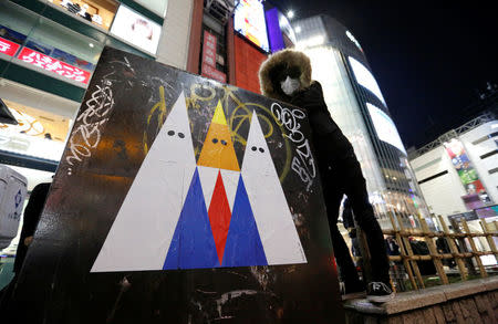 A Japanese graffiti artist known as 281 Antinuke poses for a photo with his sticker art depicting U.S. President Donald Trump in Tokyo's Shibuya shopping and entertainment district, Japan, January 27, 2017. Picture taken January 27, 2017. REUTERS/Toru Hanai