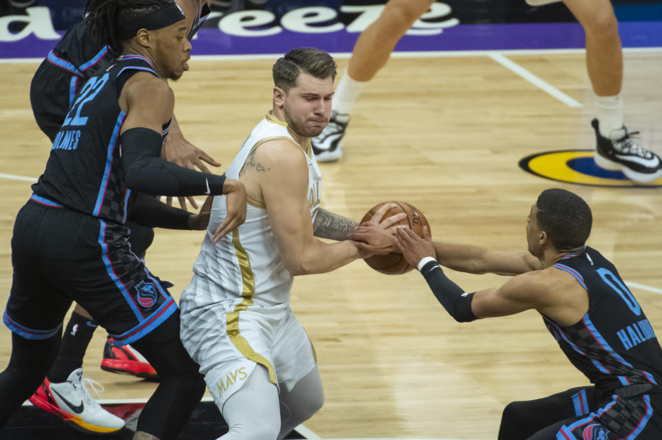 Dallas Mavericks guard Luka Doncic (77) is guarded by Sacramento Kings center Richaun Holmes (22) and guard Tyrese Haliburton (0) during the first quarter of an NBA basketball game in Sacramento, Calif., Monday, April 26, 2021. (AP Photo/Randall Benton)